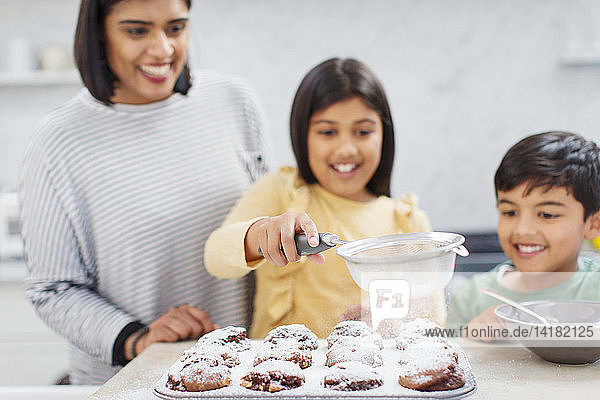 Mutter und Kinder backen Muffins in der Küche