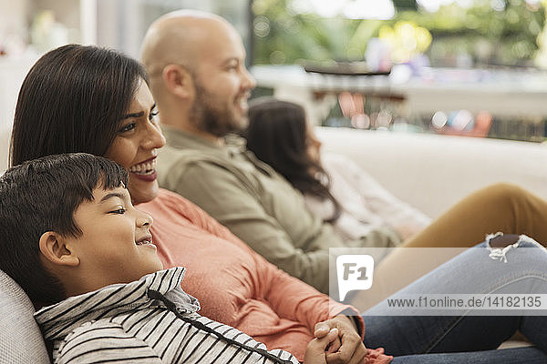 Family watching TV on living room sofa