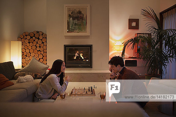 Couple playing chess in living room