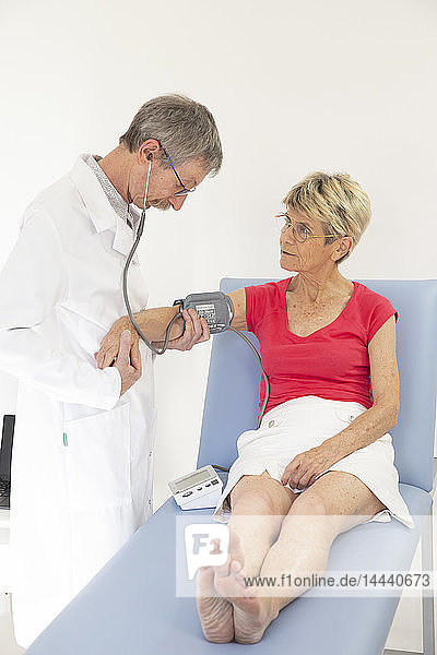 Eine Frau konsultiert einen Arzt  der ihren Blutdruck misst.