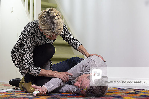Eine ältere Frau hilft einem älteren Mann  der eine Treppe hinuntergefallen ist.