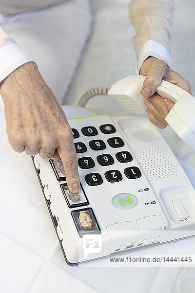 Elderly woman using a telephone with large buttons for elderly people.