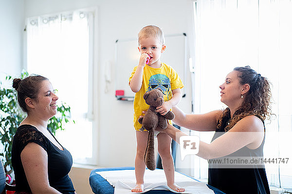 Osteopathische Konsultation bei einem Kind: das Vertrauen des Kindes gewinnen  indem die Manipulation am Spielzeug des Kindes nachgeahmt wird.