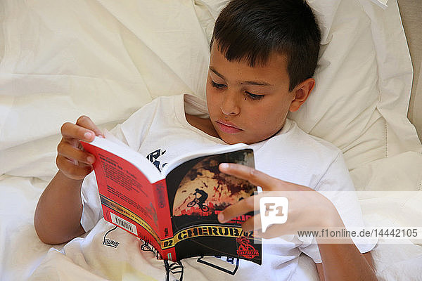 11-jähriger Junge liest im Bett in Salento  Italien.