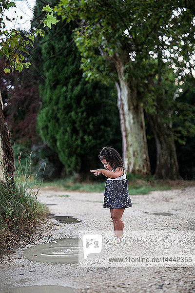 Ein kleines Mädchen spielt in einer Pfütze.