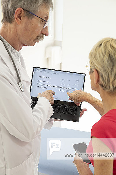 Eine Frau konsultiert einen Arzt  der ihre medizinischen Tests auf einem Computer anschaut.
