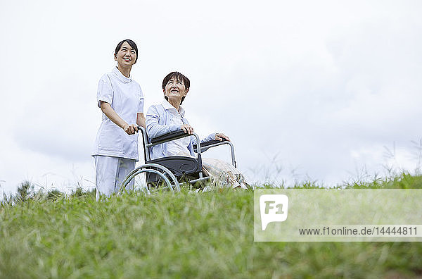 Young Japanese caregiver taking care of elder patient