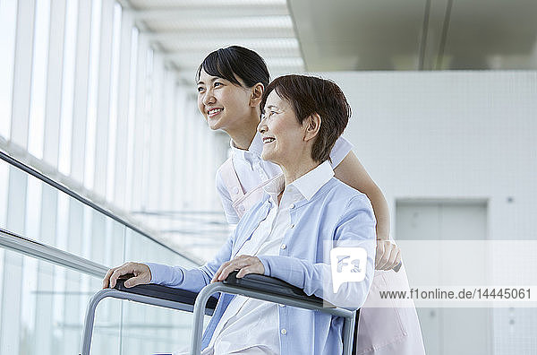 Junge japanische Pflegerin kümmert sich um älteren Patienten