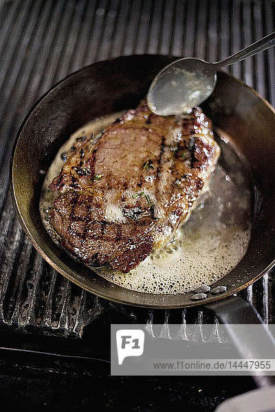 Steak wird in einer Pfanne mit Butter bestrichen