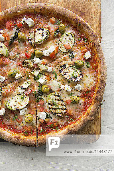 Pizza mit Feta und Gemüse auf einem Holzbrett