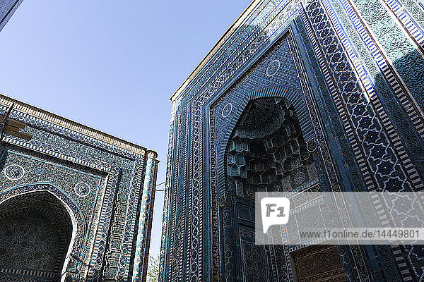 Niedrigwinkelansicht der hohen Bögen eines islamischen Madrasa-Gebäudes mit blau-weiß gemusterten glasierten Kacheln.