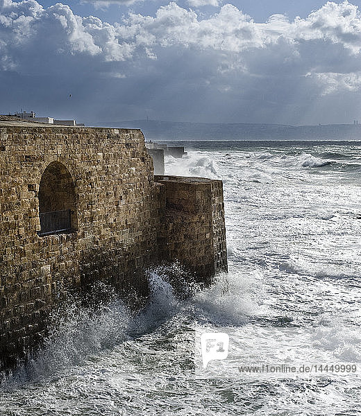 Während eines Sturms brechen Wellen gegen antike Mauern