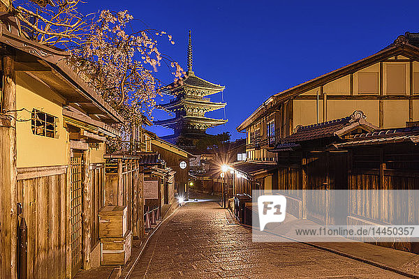 Traditionelle Häuser an einer engen Straße mit einer Pagode in der Ferne  Higashiyama bei Nacht  Kyoto  Japan.