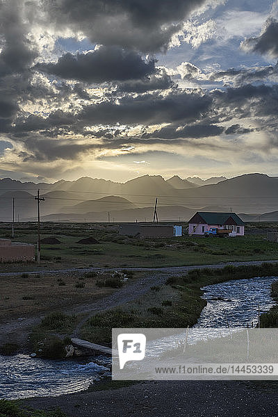 Sonnenuntergang über einem Ferienhaus an einem Fluss mit fernen Bergen  Sary Moghul  Kirgisistan.