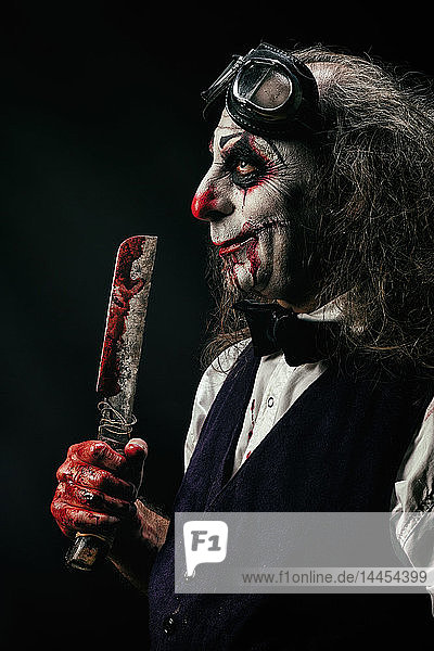 Portrait of a sadistic clown  a bloody knife in his hand