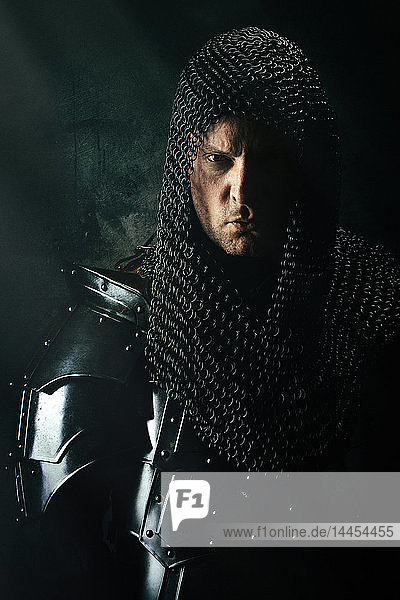 Portrait of a king in armor in the studio on a black background.
