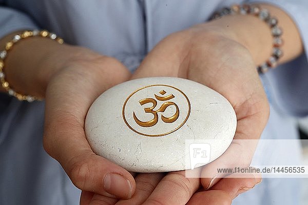 Das Om- oder Aum-Symbol des Hinduismus und Buddhismus auf einem weißen Stein.