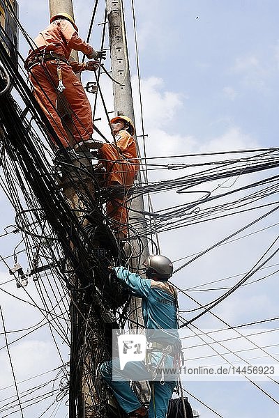 Wartungselektriker bei der Reparatur eines Strommastes. Cai Be. Vietnam.