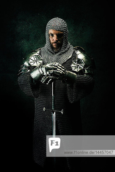 Portrait of a knight in armor in studio on black background.