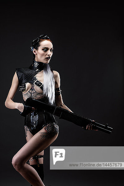 Young woman wearing latex clothes armed with a rifle
