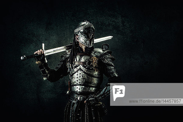 Sarmatischer Ritter im Studio auf schwarzem Hintergrund. Er hält sein Schwert auf der Schulter.