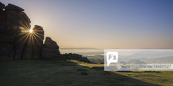Sun breaks through a gap in granite rocks at Haytor in Dartmoor National Park Bovey Tracey Devon England United Kingdom