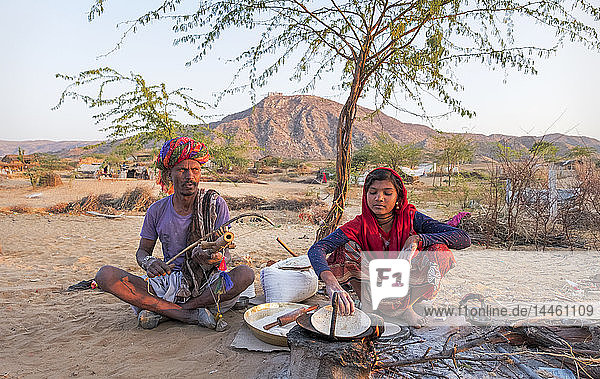 Hindu-Mädchen beim Kochen  während ihr Vater ein Musikinstrument spielt  in Pushkar  Rajasthan  Indien