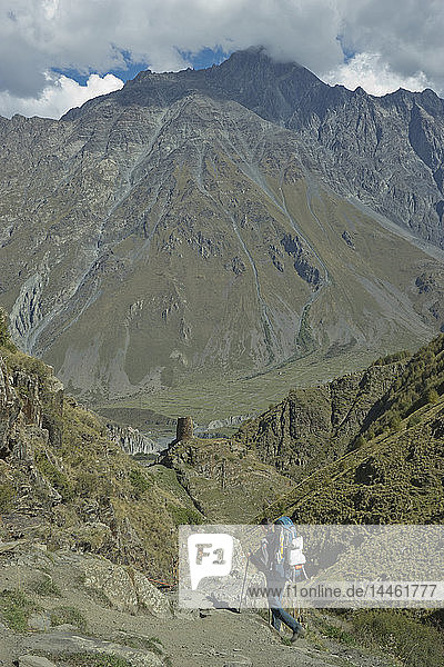 Touristen beim Trekking in der Nähe der Dreifaltigkeitskirche von Gergeti am Fluss Chkheri  unter dem Berg Kazbegi auf 2170 Metern Höhe im Kaukasus  Georgien  Zentralasien