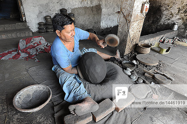 Ein Mann schlägt mit einem hölzernen Paddel einen handgefertigten  mit Holzkohle bestäubten Terrakotta-Wasserkrug in die traditionelle Form  Chhote Udepur  Gujarat  Indien