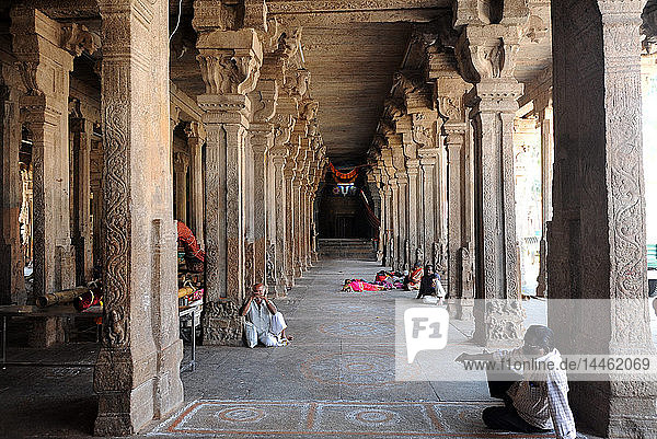 People resting in the stone pillared corridor inside the 11th century Brihadisvara Cholan temple  Thanjavur  Tamil Nadu  India
