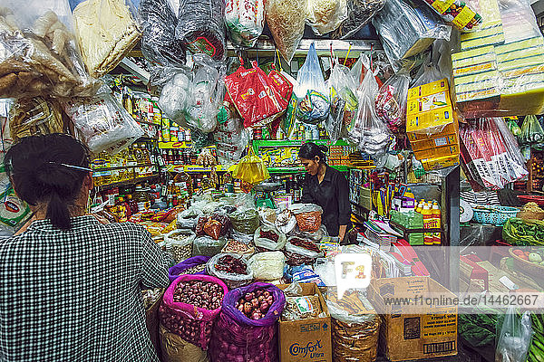 Frau und gut bestückter Verkaufsstand mit Waren und Lebensmitteln auf diesem riesigen alten Markt  Zentralmarkt  Stadtzentrum  Phnom Penh  Kambodscha  Indochina  Südostasien