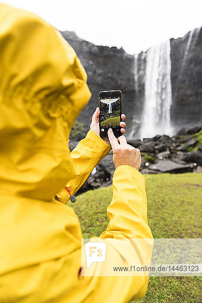 Tourist knipst Fotos mit Smartphone  Wasserfall Fossa  Insel Streymoy  Färöer  Dänemark