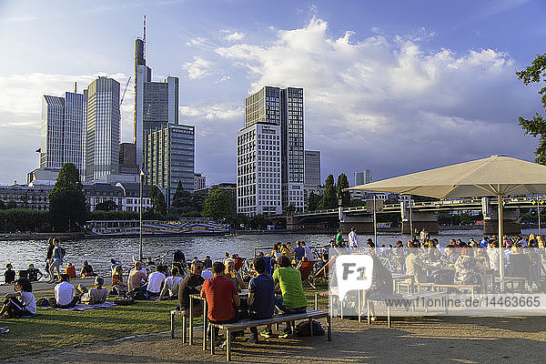 People sitting at outdoor bar beside River Main  Frankfurt  Hesse  Germany