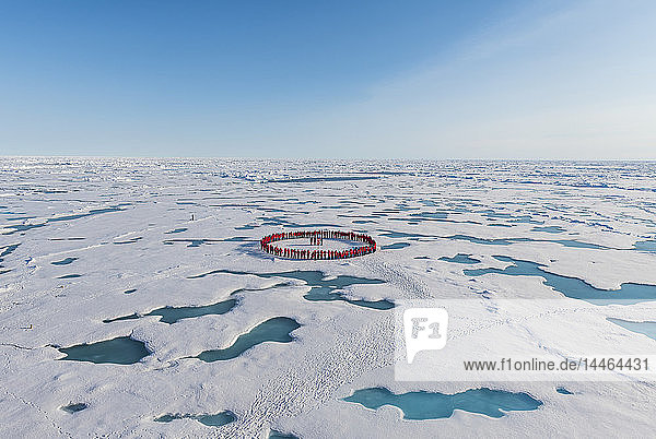 Menschen in Rot bilden einen Kreis um den Nordpol  Arktis