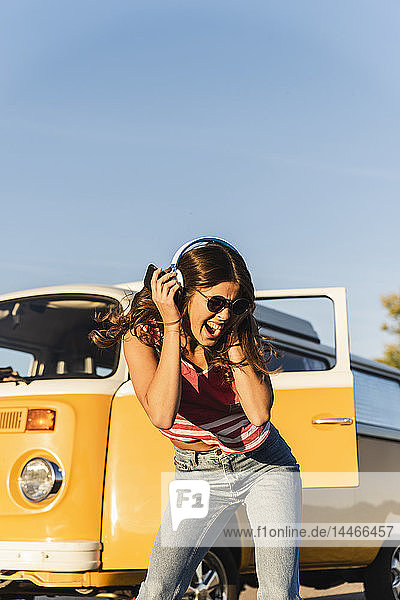 Hübsche Frau auf einer Autoreise mit ihrem Wohnwagen  tanzend  Musik hörend