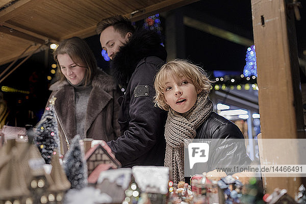 Porträt eines Jungen auf dem Weihnachtsmarkt mit seinen Eltern