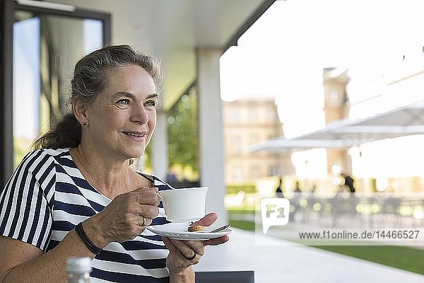 Portrait of smiling mature woman drinking cup of coffee on terrace