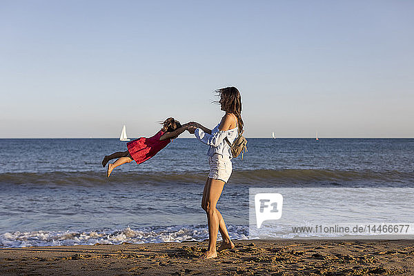 Mother and daughter having fun on the beach  pretending to fly