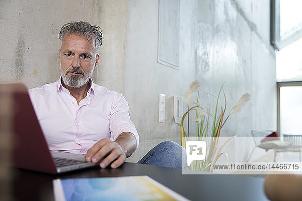 Businessman sitting at table in a loft using laptop