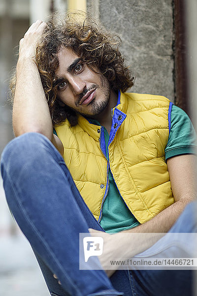 Portrait of smiling young man with beard and curly hair wearing yellow waistcoat