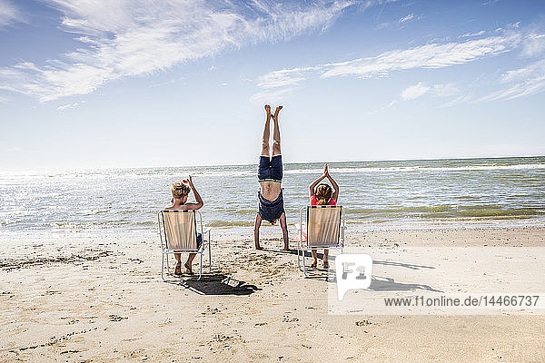Niederlande  Zandvoort  Kinder klatschen für Vater beim Handstand am Strand in die Hände