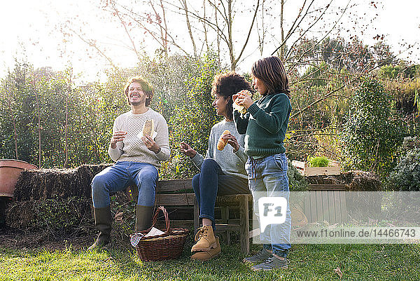 Glückliche Familie sitzt im Garten  macht eine Pause  isst Sandwiches