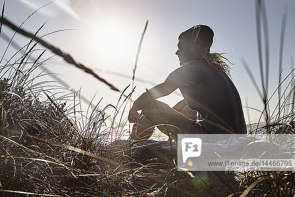 Portugal  Algarve  Mann sitzt bei Sonnenuntergang am Strand