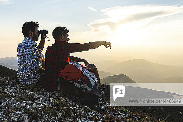 Italy  Monte Nerone  two hikers on top of a mountain enjoying the view at sunset