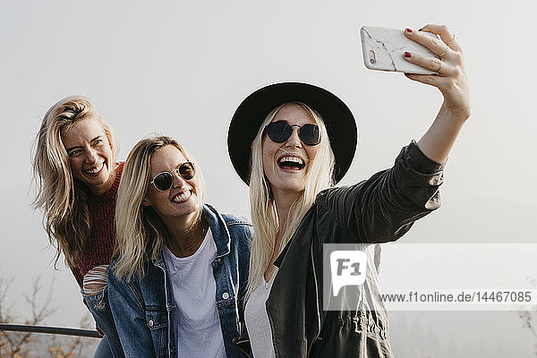 Three happy young women taking a selfie outdoors