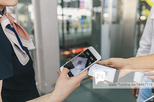 Mitarbeiter einer Fluggesellschaft scannt QR-Codes von Passagieren mit einem Smartphone am Flughafen