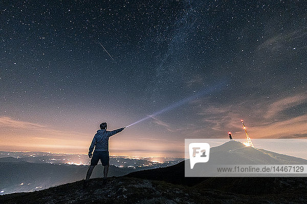Italien  Monte Nerone  Silhouette eines Mannes mit Fackel unter Nachthimmel mit Sternen und Milchstraße