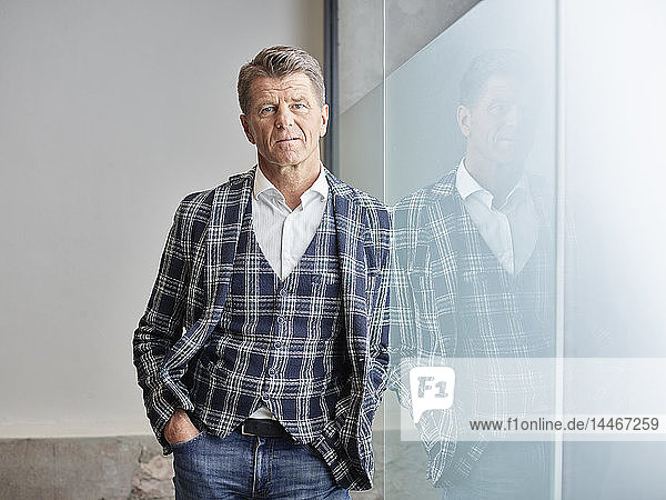 Portrait of businessman leaning against glass wall