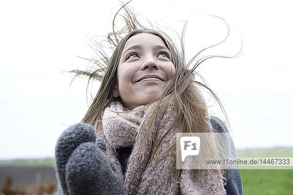 Porträt eines lächelnden Mädchens mit wehendem Haar im Winter mit Blick nach oben