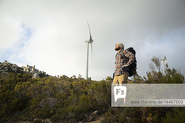 Spanien  Andalusien  Tarifa  Mann auf einer Wanderung mit Windkraftanlage im Hintergrund